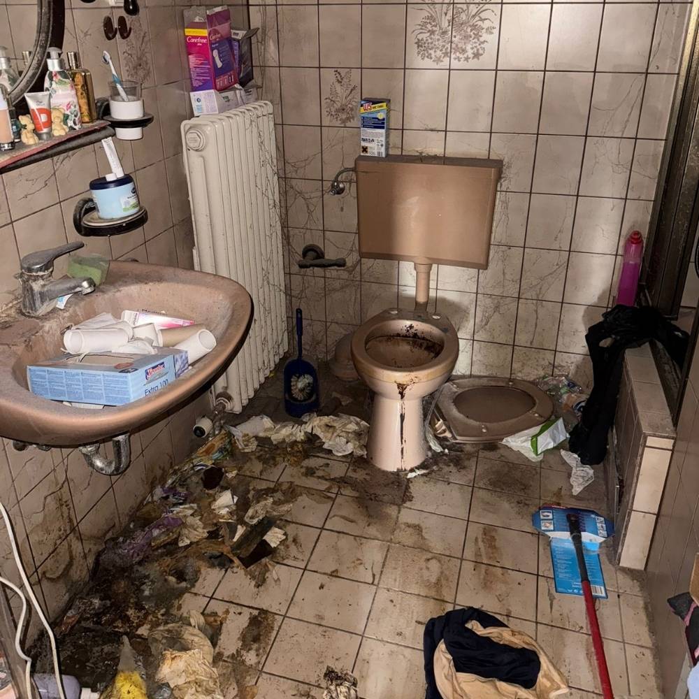 Before cleanup: a bathroom with accumulated debris and soiling.
