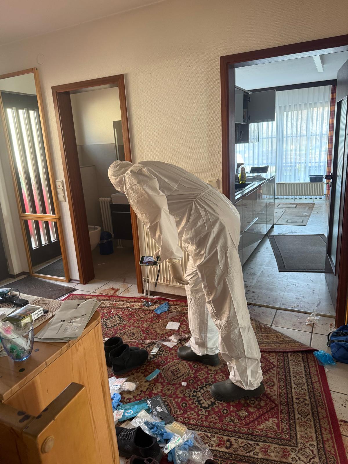 Worker in protective clothing inspecting a furnished room during cleanup