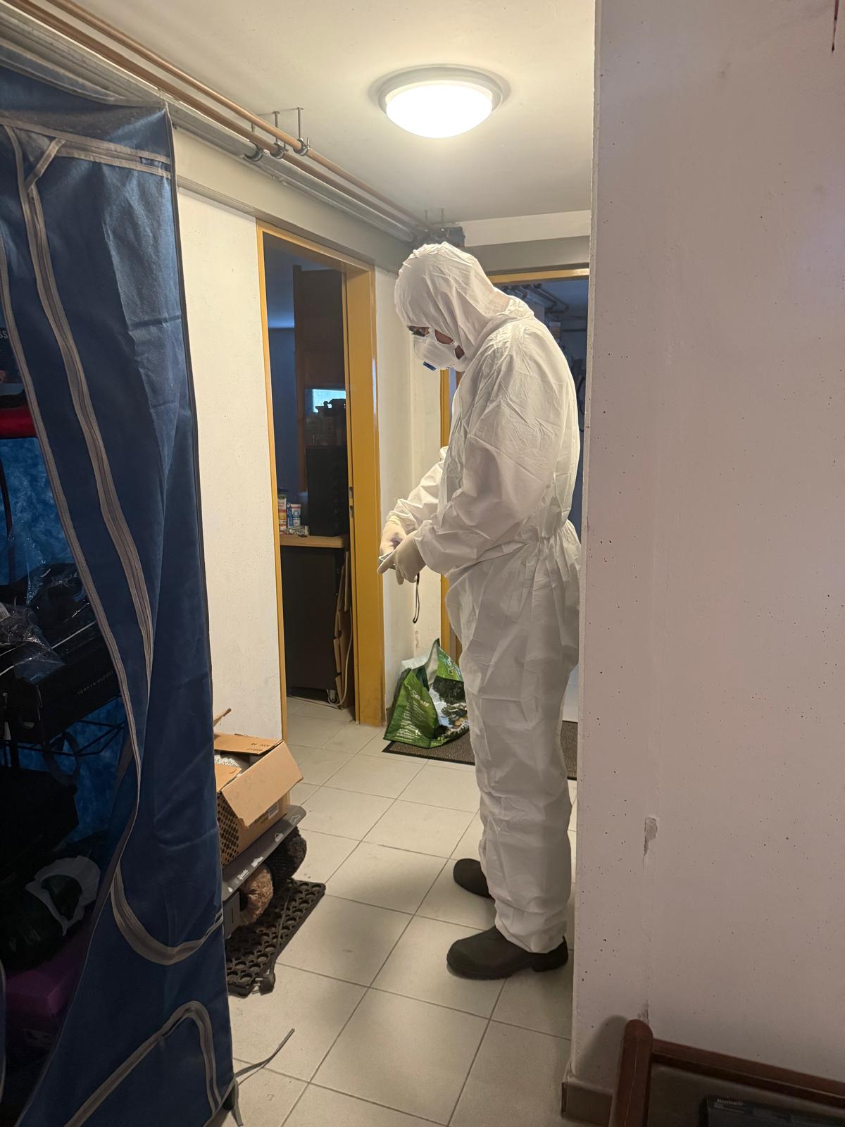 Cleanup worker using a sprayer beside a screened work area