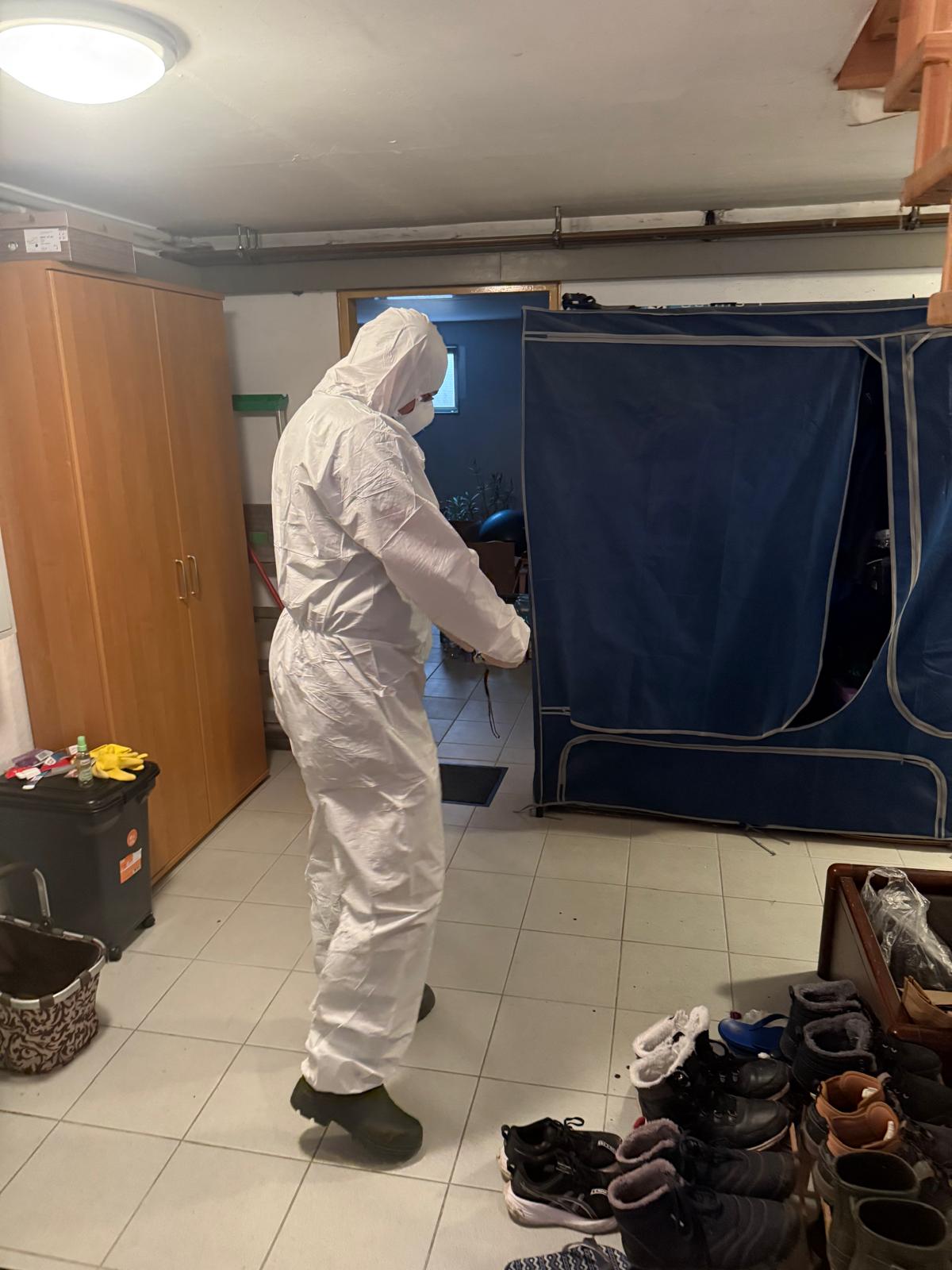 Worker in protective clothing treating an area near a screened doorway