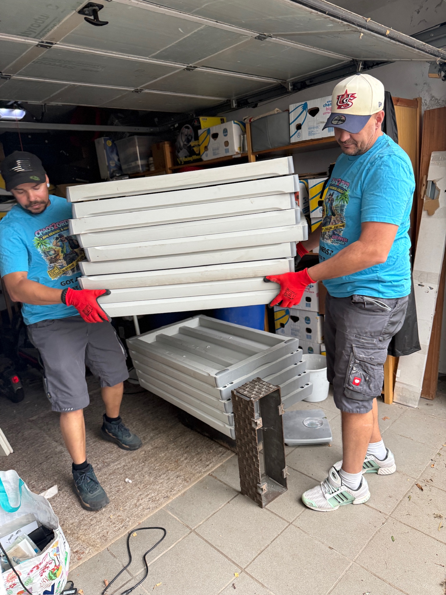 Chaos2Order team carrying stacked metal panels out of a garage